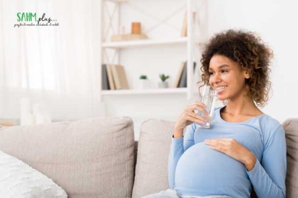 Pregnant woman drinking water to stay hydrated and healthy